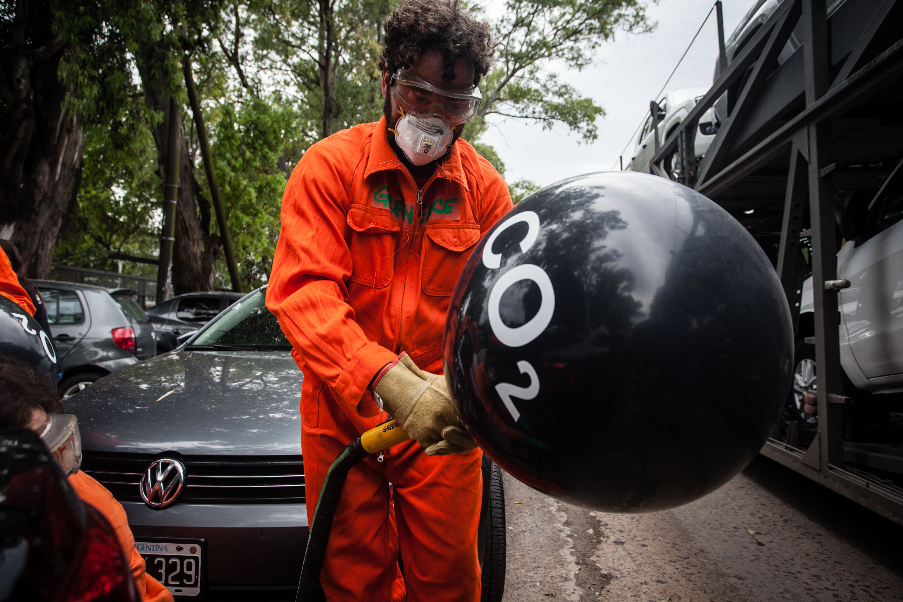 Einen Greenpeaceaktivisten, welcher mit einem Tankschlauch einen Luftballon aufblast. Auf dem Luftballon steht 