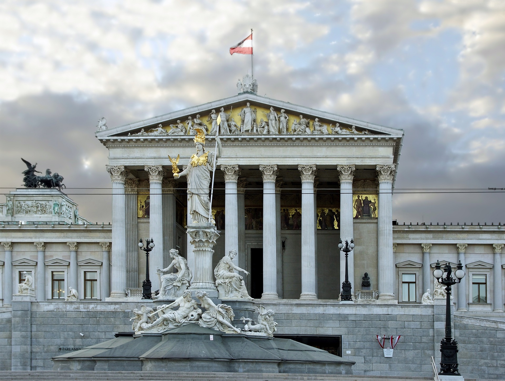 Frontalansicht des österreichischen Parlaments mit gehisster österreichischer Flagge.