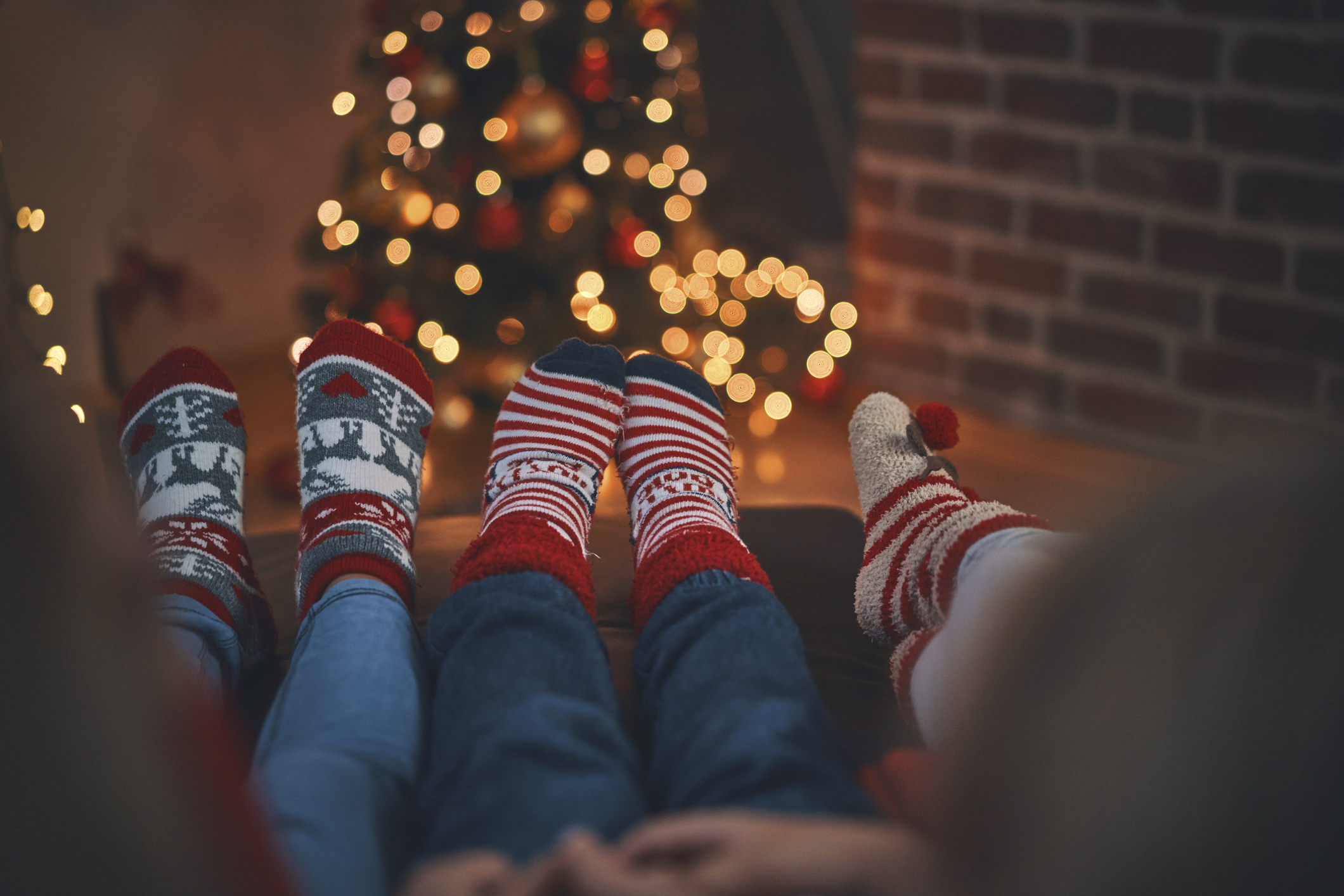 Drei Paar Beine mit Weihnachtssocken an den Füßen