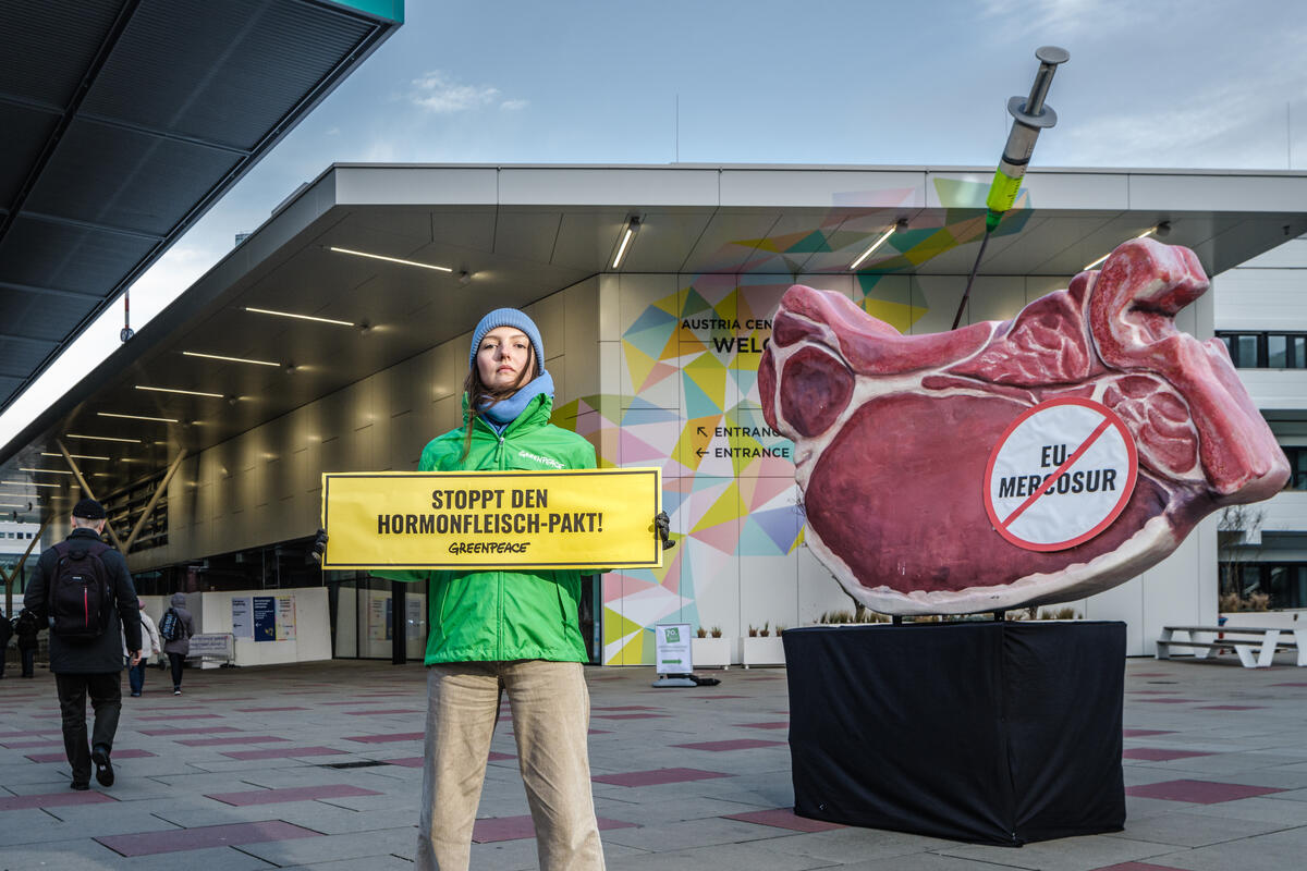 Greenpeace-Aktivistin mit einem Schild mit der Aufschrift 