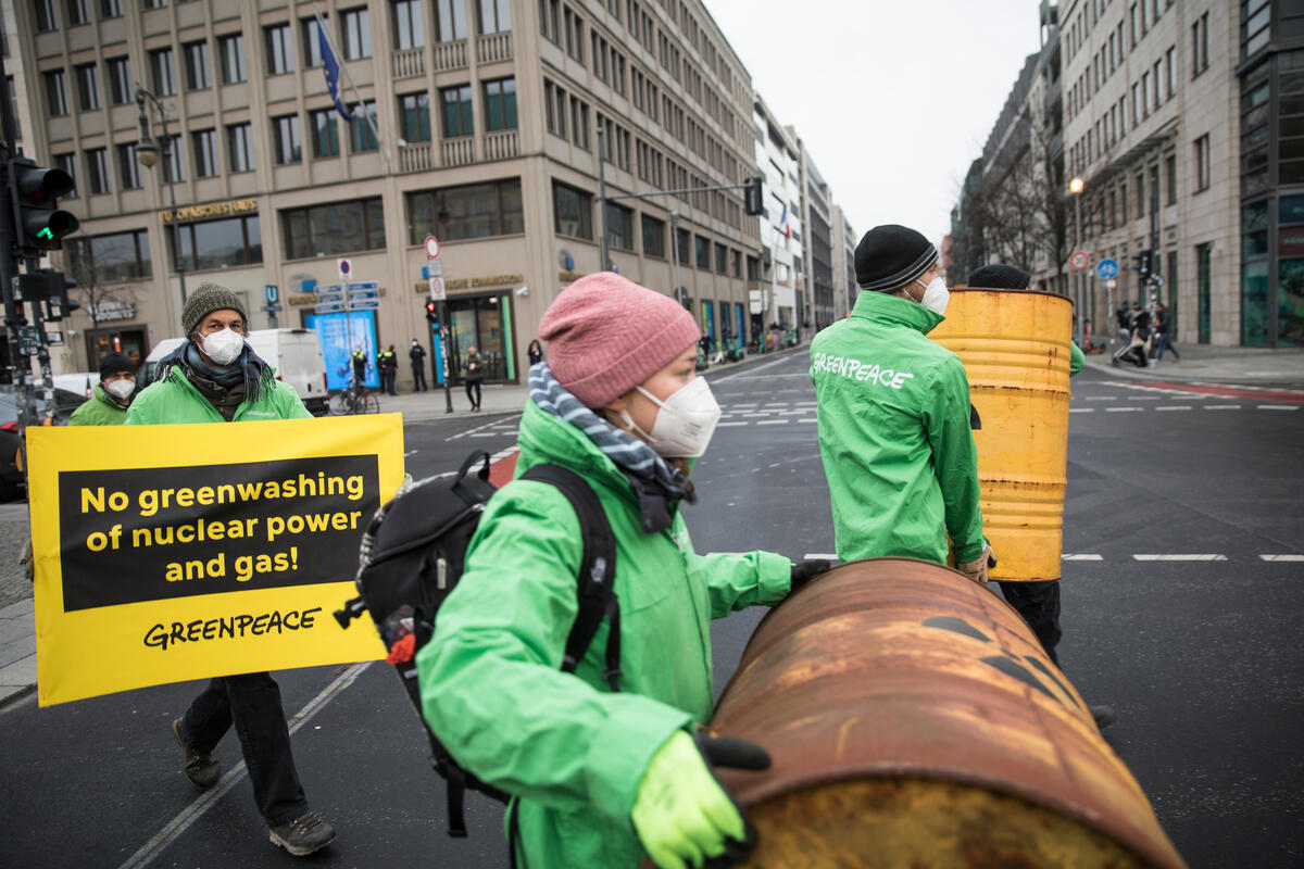 Greenpeace-Aktivist:innen tragen Banner über die Straße