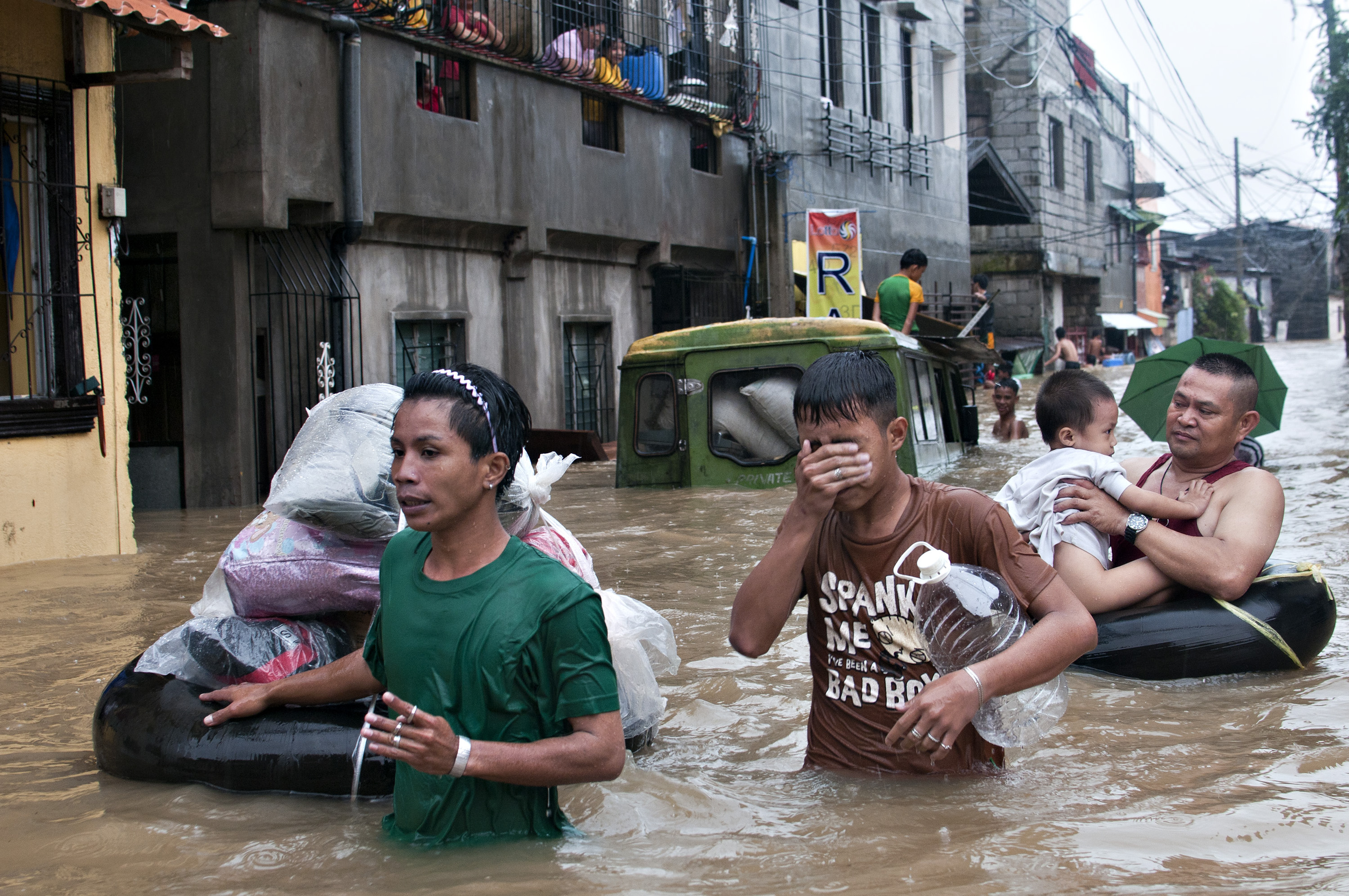 Menschen waten durch hüfthohes Hochwasser in Manila