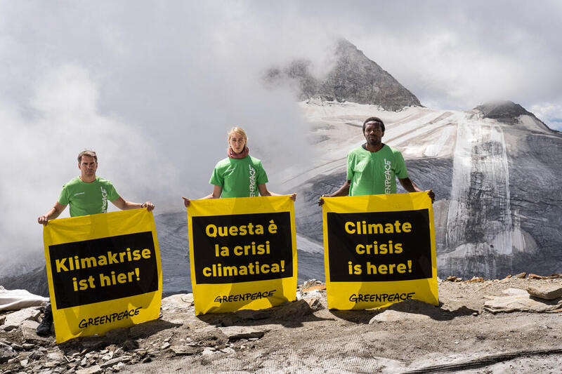 Drei Aktivist:innen stehen auf dem Gletscher und halten Banner mit der Aufschrift 