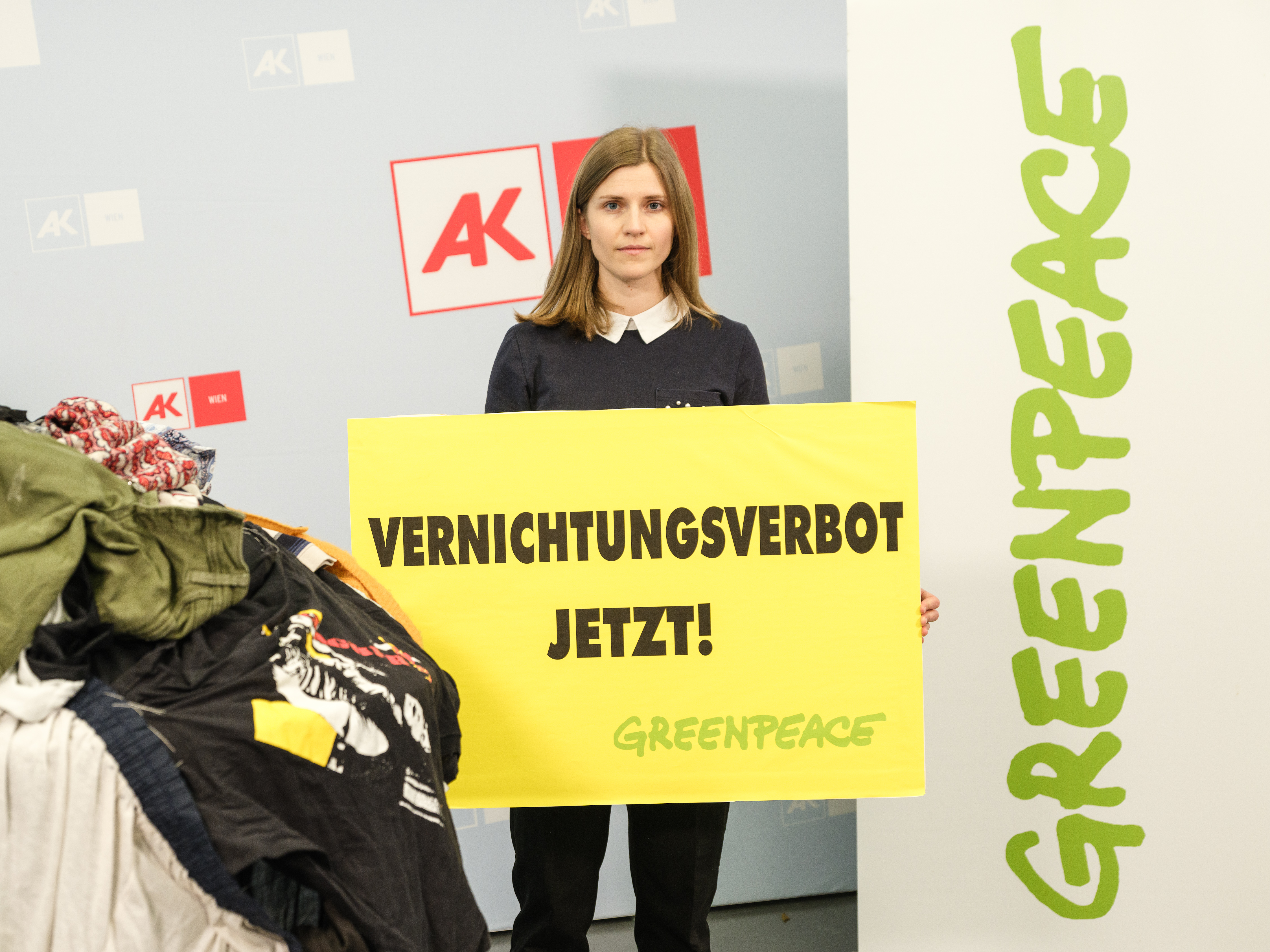Man sieht eine Greenpeace Campaignerin mit einem Schild mit der Aufschrift 