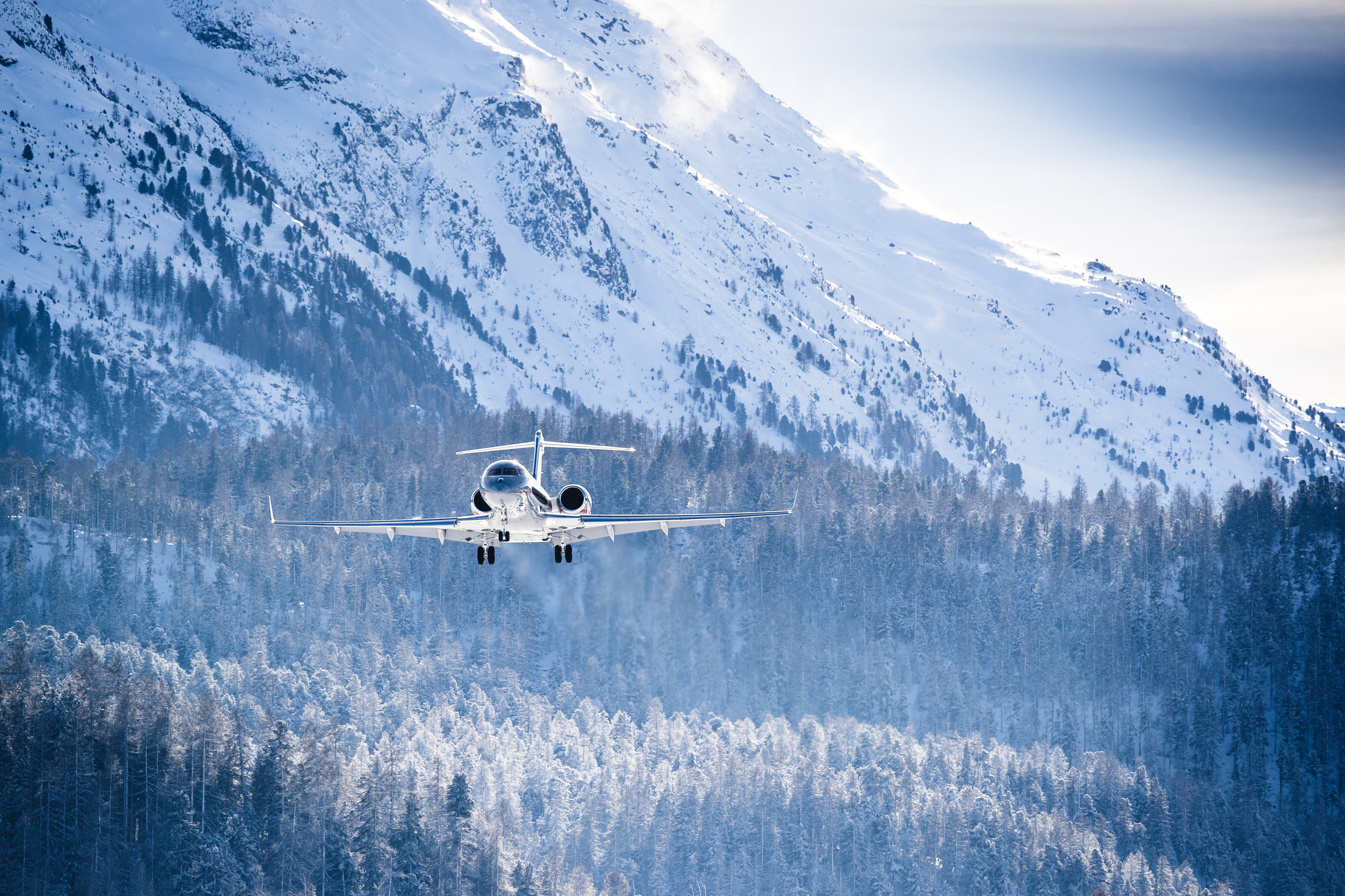 Privatjet fliegt über verschneite Berge