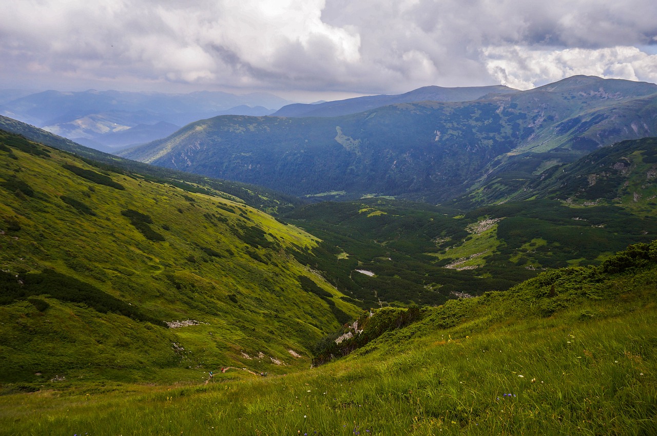 Ein Tal mit grünem Gras zwischen Bergen und Hügeln.