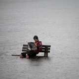 Mann liest Zeitung auf einer Bank im Überschwemmungsgebiet